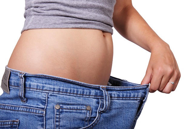 Girl pulling out the waistband of her pants to show weight loss progress.